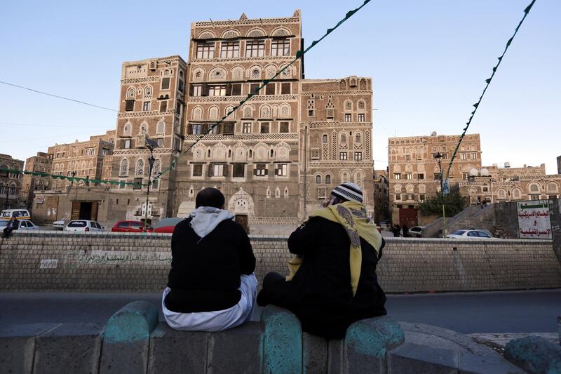 Yemenis sit in front of historic buildings in the old quarter of Sana'a. EPA