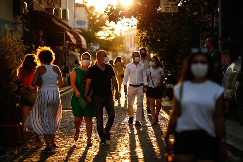 Tourists wearing masks to protect from the spread of the coronavirus walk at the Aegean Sea town of Ayvalik, Turkey. AP Photo
