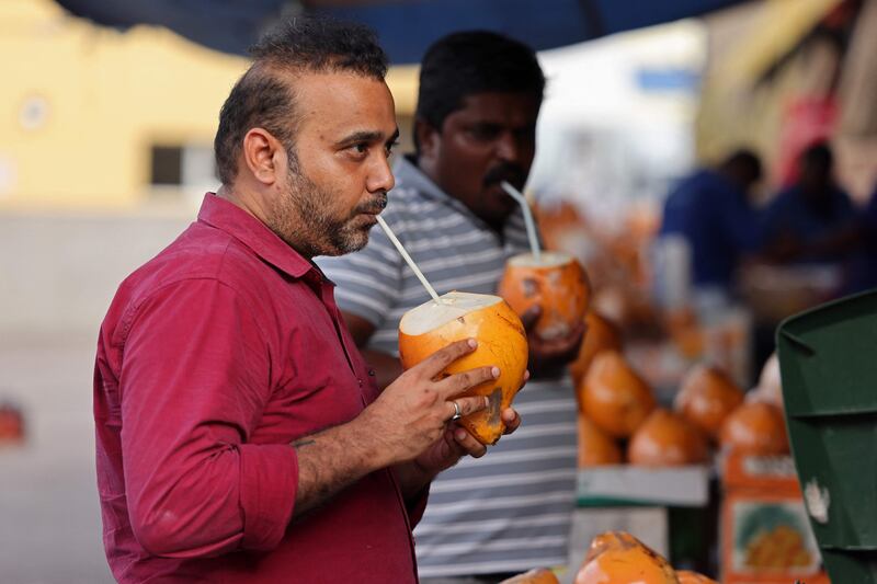 People drink coconut water at a market in Dubai to cope with the hot weather. AFP