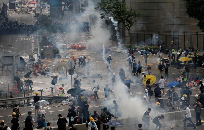 Riot police fire tear gas toward protesters. AP