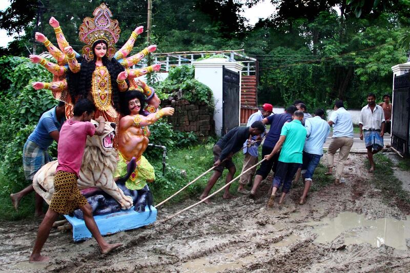 Indian devotees pull a clay idol of the Hindu Goddess Durga across a muddy area following rains in Allahabad.  AFP