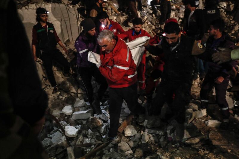 Syrian civil Defence volunteers carry a victim amid the rubble following an explosion in the rebel-held city of Idlib. Sameer Al-Doumy / AFP