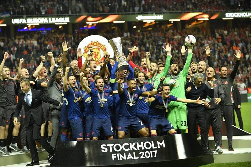 Manchester United players and staff celebrate with the Europa League trophy. Peter Powell / EPA