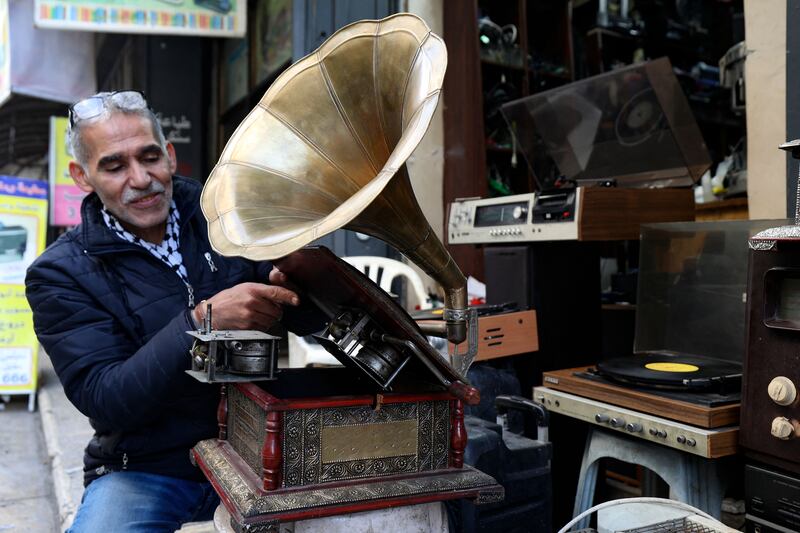 Palestinian Jamal Hemmou checks an antique gramophone (phonograph) record player in front of his shop in the occupied-West Bank city of Nablus, on January 17, 2023.  - Hemou, 58, is the last of his kind in Nablus in the West Bank city: He runs the only store in Nablus repairing and selling vinyl records and their players.  Like much of the world, Nablus is attuned to digital music, but Hemmou told AFP working with vinyl was about preserving Palestinian "heritage. " (Photo by JAAFAR ASHTIYEH  /  AFP)