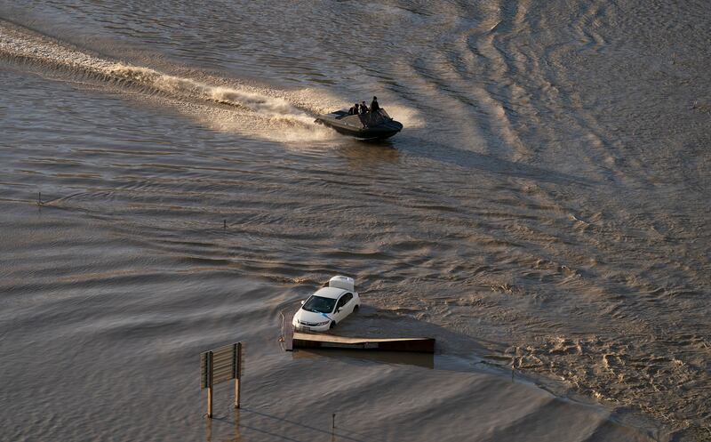 A boat speeds along a flooded motorway.