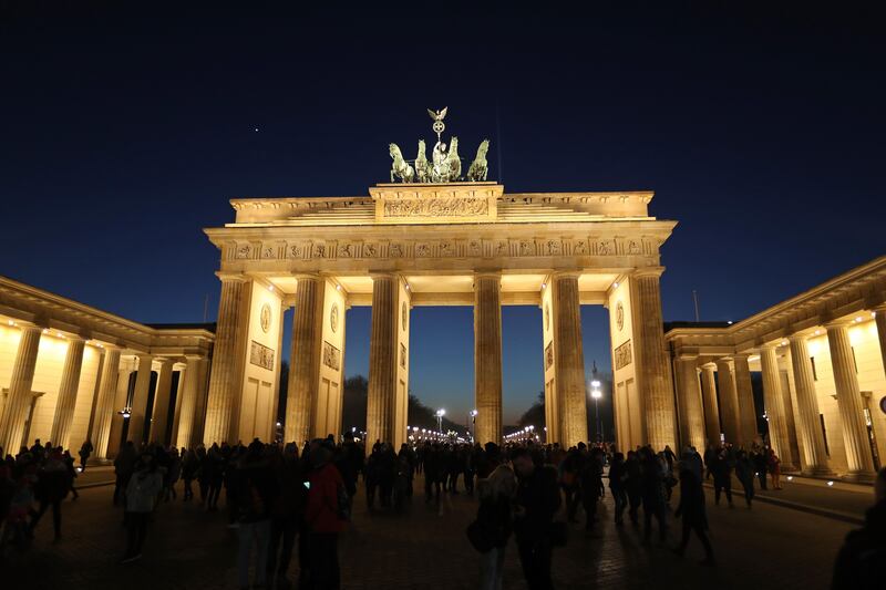 BERLIN, GERMANY - FEBRUARY 14:  Visitors stand at the illuminated Brandenburg Gate at twilight on February 14, 2017 in Berlin, Germany. The monument is among Berlin's main tourist attractions.  (Photo by Sean Gallup/Getty Images)
