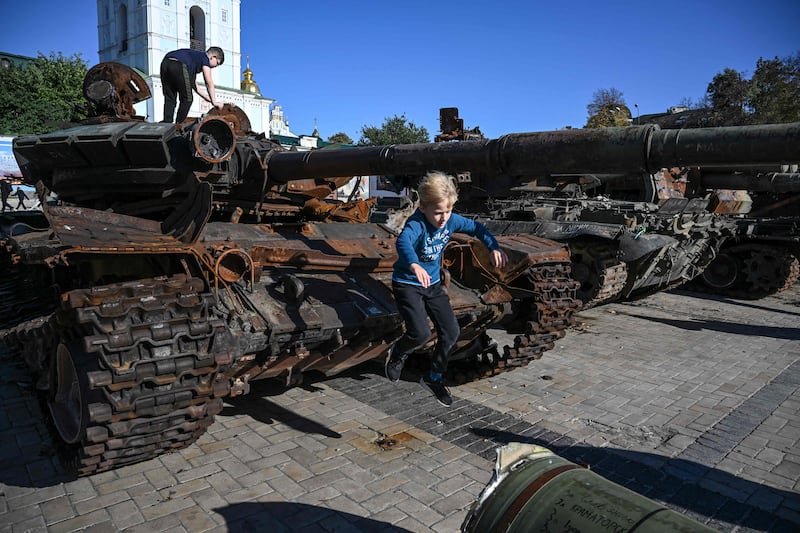A boy playing on a destroyed Russian tank on display in Kyiv. AFP