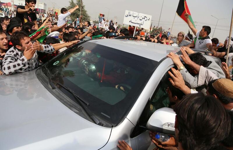A car carrying players of the Afghan team and showing off the trophy is surrounded by fans in Kabul. S Sabawoon / EPA