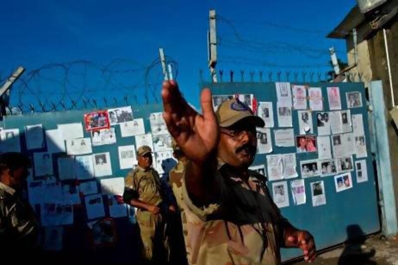 An Indian security official clears the road in front of portraits of missing pilgrims pasted on the gates of the Jolly Grant Airport in Dehradun, state capital of Uttarakhand.