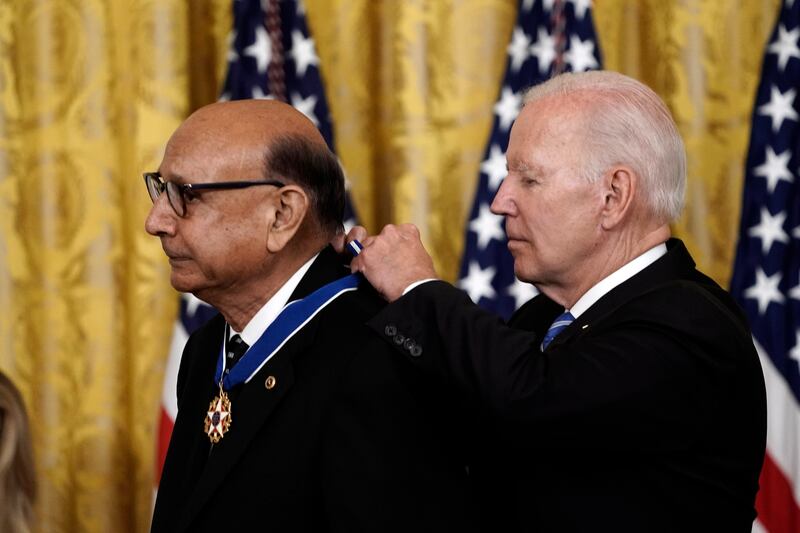 Mr Biden presents Mr Khan with his medal. EPA