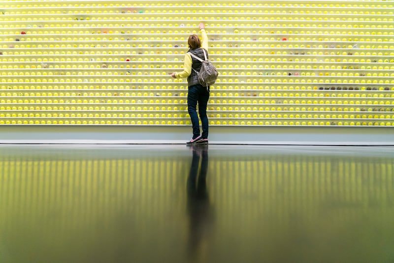 A visitor views the 12,000 tennis balls comprising 'Mayfair Tennis Ball Exchange' by artist David Shrigley at the Stephen Friedman Gallery in London on Thursday. Visitors are invited to bring in an old tennis ball to swap with one of the new ones, creating a gradually evolving artwork. PA