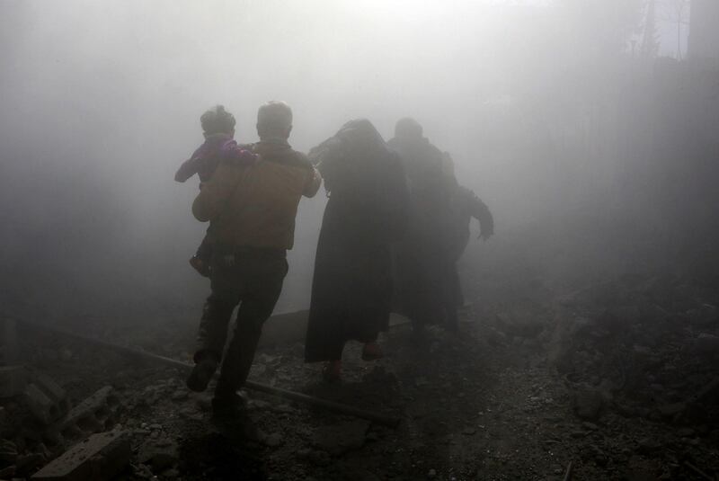 A Syrian family flees from regime air strikes in the rebel-held town of Jisreen on February 8, 2018, the fourth consecutive day of heavy bombing raids on the rebel-held enclave of Eastern Ghouta near Damascus. Abdulmonam Eassa / AFP