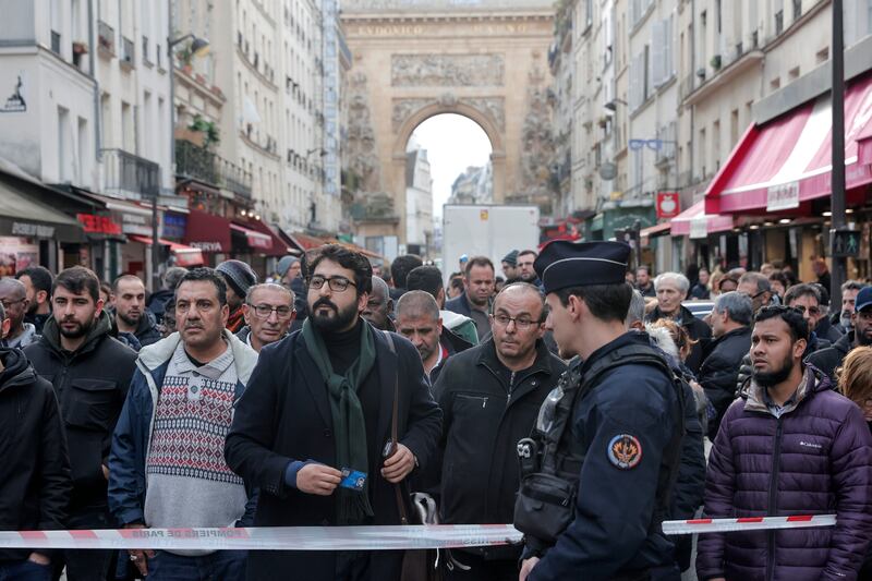 People gather behind a police tape at the crime scene. AP