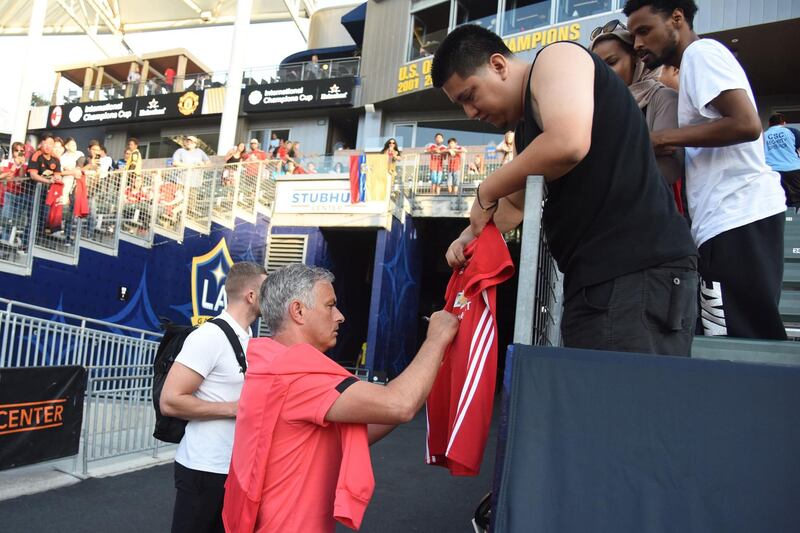 Manchester United's coach Jose Mourinho signs an autograph before the start of the match. AFP