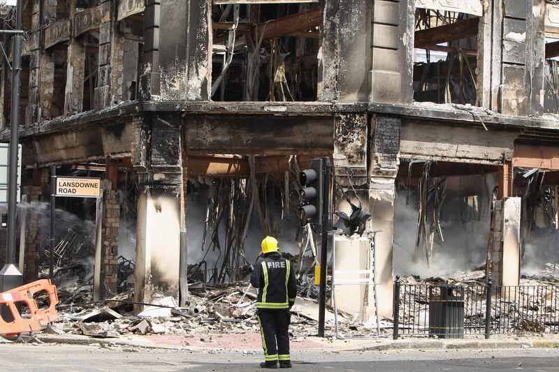 A fireman stands near the smouldering remains of a burnt out building after riots on Tottenham High Road.