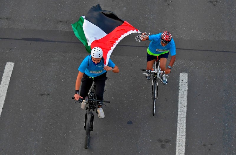 Dubai residents carry the UAE flag as they ride on the Sheikh Zayed Road. Karim Sahib / AFP