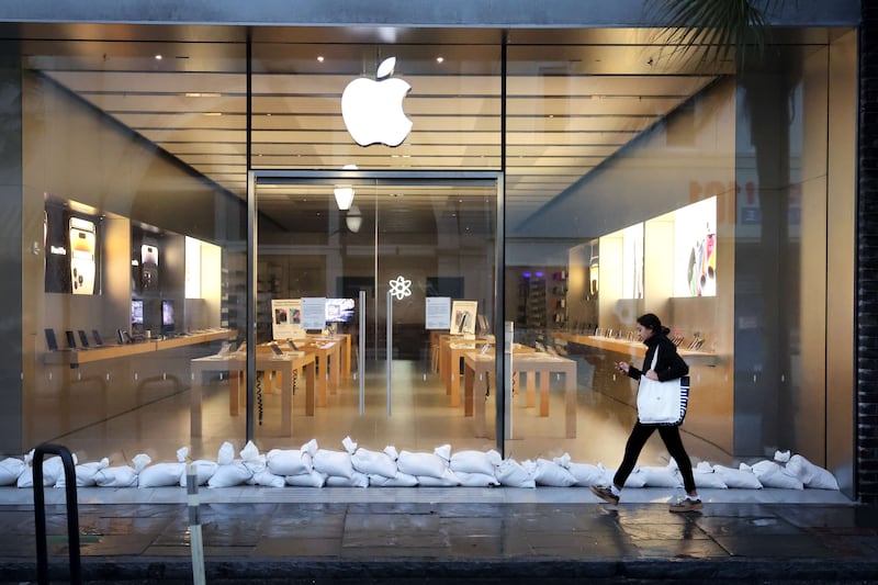 A woman walks past a shuttered and sandbagged Apple store in the historic district of Charleston. Getty Images / AFP