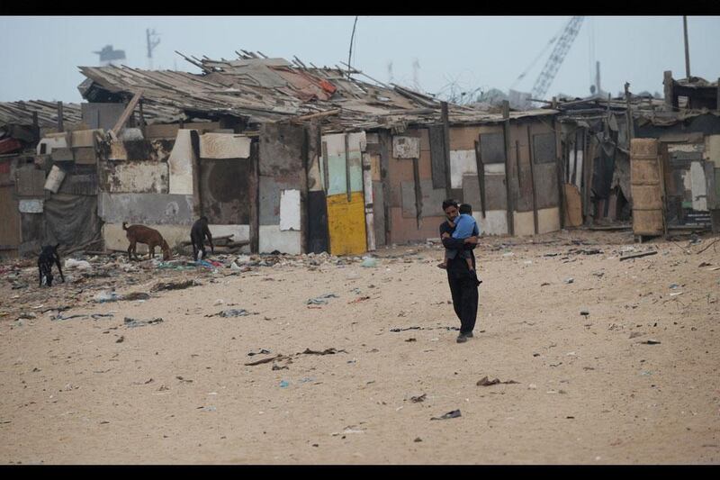 Family time: Abdul Raziq takes a walk with his baby brother Abdul Qadeer in his arms outside the cluster of wooden shacks that he calls home.