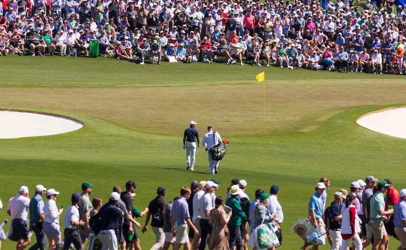 Tiger Woods and his caddie Joe LaCava walk onto the second green surrounded by fans. EPA