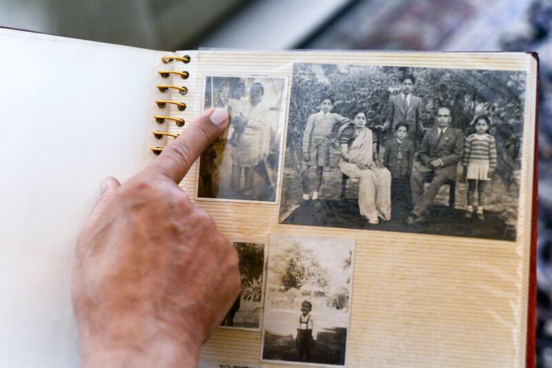 Vinay Varma points to a photograph of him as a small child in his mother's arms, in Rawalpindi, before the 1947 partition. The album page contains other family photographs from the 1940s. Khushnum Bhandari / The National

