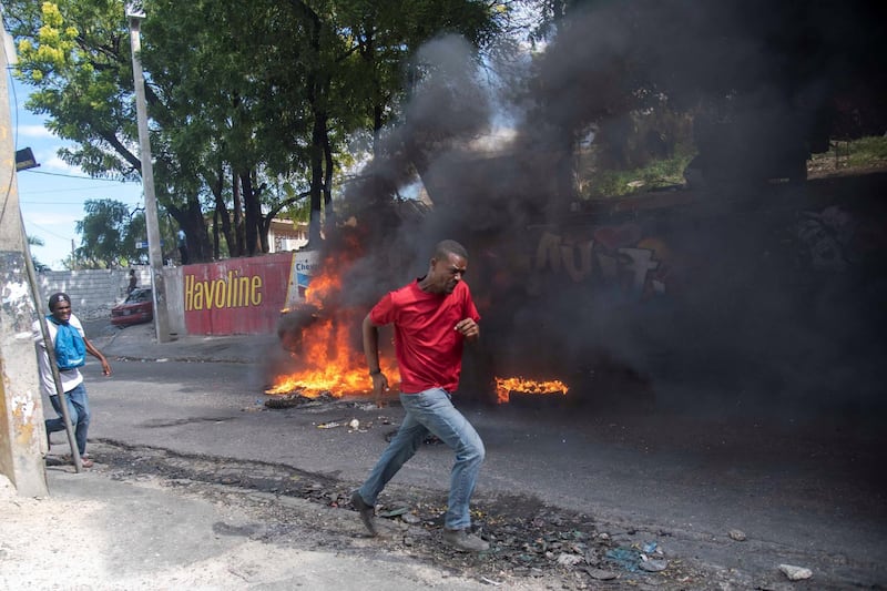 A person runs pass a burning blockade during a protest in Port-au-Prince. EPA