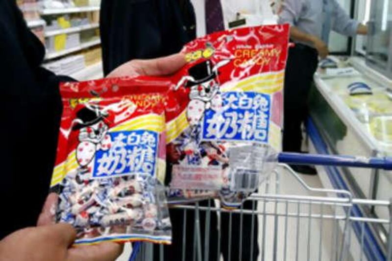 Malaysian health ministry's food safety and quality division officials display packs of the popular "White Rabbit Creamy Candy" from China --in which neighbouring Singapore found the potentially deadly chemical melamine-- at a supermarket in Kuala Lumpur on September 23, 2208.  Malaysia has widen its ban on Chinese dairy products on September 23, 2008 to include candies, chocolates and all foods containing milk as 53,000 infants in China have become sick after drinking formula laced with melamine, a chemical used in plastics which can also make milk appear to be full of protein.   MALAYSIA OUT   AFP PHOTO *** Local Caption ***  466563-01-08.jpg