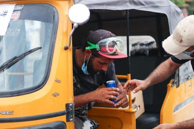Tuk-tuk driver Karad Hussein rinses his eyes with Pepsi to reduce the effects of tear gas. Pesha Magid for The National