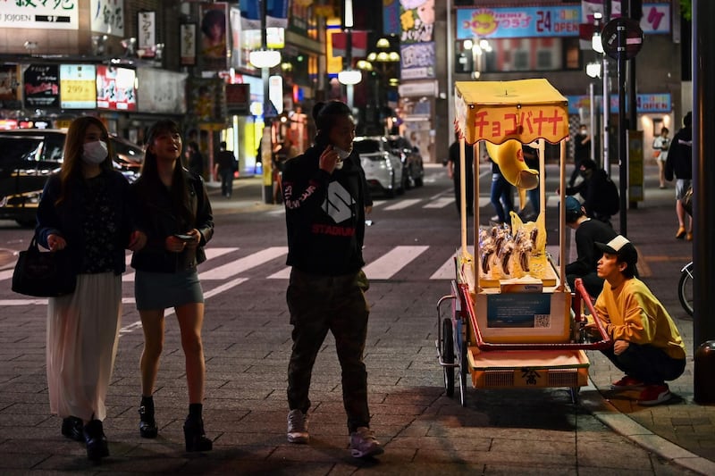 People walk at night along a street in Tokyo.  AFP