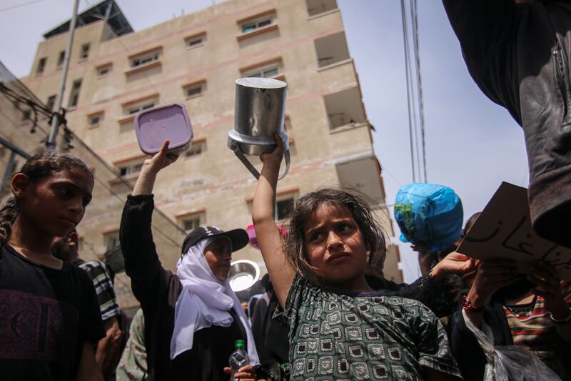 Displaced Palestinians carry empty pots and pans as they call for more aid during a demonstration in Deir Al Balah, central Gaza, on April 25. Bloomberg