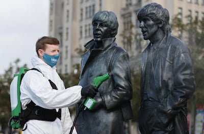 A man disinfects a statue of the Beatles amid the outbreak of the coronavirus disease (COVID-19), in Liverpool, Britain October 1, 2020. REUTERS/Carl Recine