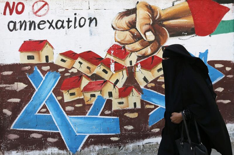 A Palestinian woman walks past a mural in protest of Israel's plan to annex parts of the Israeli-occupied West Bank, in Rafah in the southern Gaza Strip.  Reuters