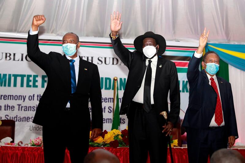 Chairman of the Transitional Military Council of Sudan Abdel Fattah (L) and South Sudan President Salva Kiir (2nd L) greets people gathering during the singing of the Sudan peace deal with the rebels groups in Juba, South Sudan, on 31 August 2020. / AFP / Akuot Chol
