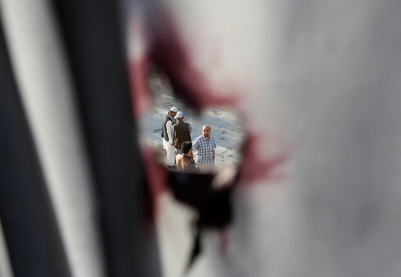 Men are seen through a hole in a window curtain with blood stains at a Shi'ite Muslim mosque after yesterday's attack in Kabul, Afghanistan. Mohammad Ismail / Reuters