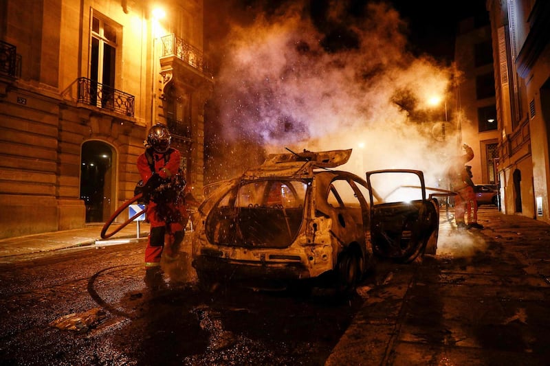 Firefighters extinguish a burning car near the Champs-Elysees in Paris. AFP