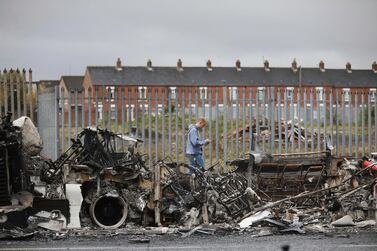 A man walks past a destroyed bus on Shankill Road in Belfast after violence in April. AP