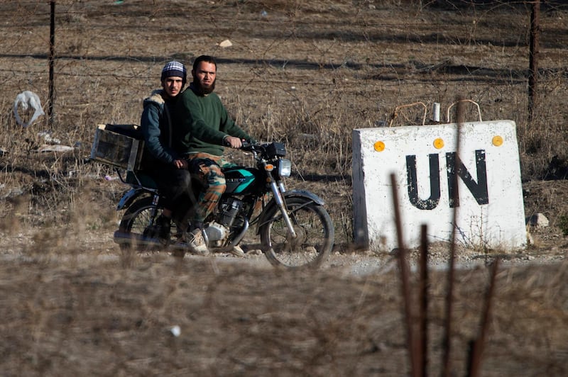 FILE - in this Nov. 2016, file photo, two men, not specified which group of rebels, ride a motorcycle towards an abandoned UN base at Syria's Quneitra border crossing between Syria and the Israeli-controlled Golan Heights. Israelâ€™s defense minister says the countryâ€™s border crossing with Syria is reopening for U.N. personnel and will resume operating as before the civil war erupted next door. Avigdor Lieberman visited the Quneitra crossing on Thursday, Sept. 27, 2018. (AP Photo/Ariel Schalit, File)
