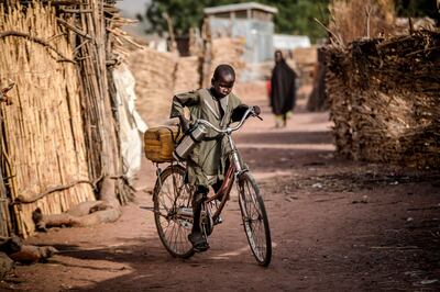 A boy rides a bike near his house at Malkohi refugee camp in Jimeta, Adamawa State, Nigeria on February 19, 2019, four days ahead of the country's General elections set for February 23 after a last-minute rescheduling. Malkohi is a camp for internal displaced who fled their homes as Boko Haram insurgents advanced across north-eastern Nigeria. From their homes on the outskirts of Yola, capital of presidential candidate Atiku Abubakar's home state Adamawa, Malkohi residents say they feel forgotten. / AFP / Luis TATO

