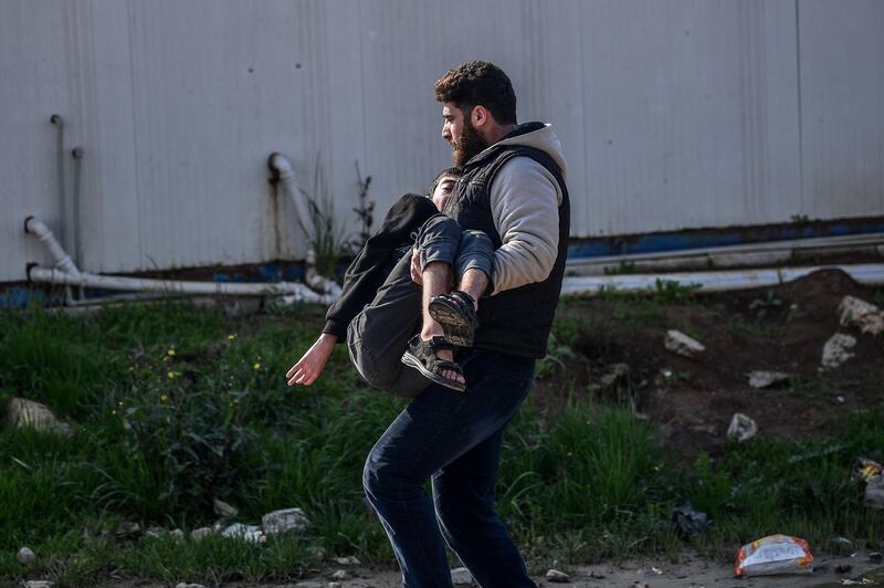 TOPSHOT - A man carries an injured man after a rocket hit a road in the Reyhanli district in Hatay province, near the Turkey-Syria border, on January 31, 2018.
A 17-year-old girl was killed in a Turkish border town on January 31 by rockets launched from Syria, officials said, as Turkey presses its offensive against a Syrian Kurdish militia. Another individual was also hurt after two rockets hit Reyhanli in Hatay province from northern Syria, the district mayor Huseyin Sanverdi said in a statement, and at least one new rocket hit a street not far a few hours later in the centre of Reyhanli, according to an AFP at the scene. Ankara began a cross-border operation dubbed "Olive Branch" supporting Syrian rebels with air strikes and ground troops in northern Syria against the People's Protection Units (YPG) militia and its western enclave of Afrin on January 20. / AFP PHOTO / OZAN KOSE