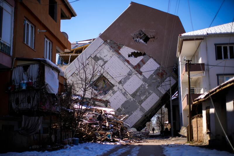 A man walks near a damaged building that leans on a neighbouring house in Golbasi, Turkey. AP