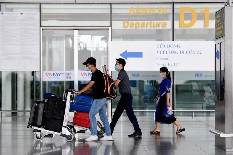 Passengers walk with their luggage at the departure terminal at Noi Bai International Airport in Hanoi on September 16, 2020. Vietnam said September 16 it will resume international commercial flights to and from six Asian destinations, months after a suspension due to the COVID-19 coronavirus. / AFP / Nhac NGUYEN
