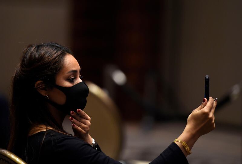 A Bahraini reporter checks her makeup and facemask ahead of a press conference by the US Special Representative for Iran and Senior Adviser to the Secretary of State and Bahrain Foreign Minister in Bahraini capital Manama on June 29, 2020.  / AFP / Mazen Mahdi
