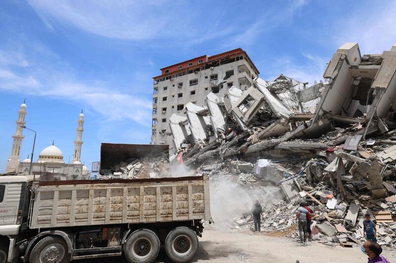 Egyptian workers and bulldozers sent from Egypt help on June 9, 2021 remove the rubble of uildings destroyed by Israeli air strikes last month. After brokering a ceasefire between the Israelis and Gaza's rulers of the Hamas movement that garnered Egypt international diplomatic clout, Cairo is now banking on a $500 million reconstruction project to shore up its regional political influence. Last month, Egypt pledged half a billion dollars to rebuild the blockaded Palestinian enclave, which was bombarded by Israel for 11 days during heavy fighting with Hamas which ended with an Egyptian-brokered ceasefire on May 21. / AFP / MOHAMMED ABED
