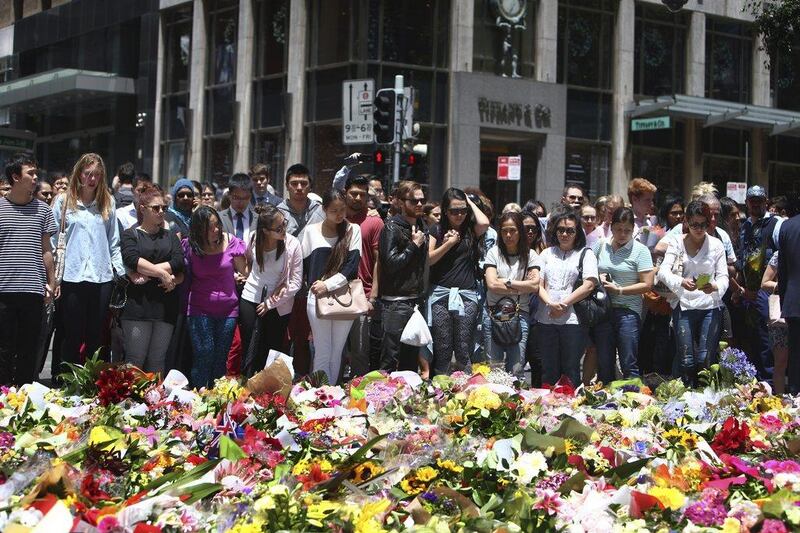 Staff members from the Lindt Chocolat Cafe with their arms linked pay tribute to their colleague who lost his life during a siege at the popular coffee shop at Martin Place in the central business district of Sydney. Steve Christo / AP Photo