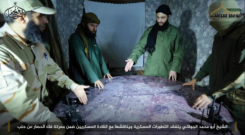 FILE -- This undated file photo, shows Abu Mohammed al-Golani, second right, then leader of Fatah al-Sham Front, in pictures posted by the group, discussing battlefield details with field commanders over a map, in Aleppo, Syria. Russia's military announced Wednesday, Oct. 4, 2017, that it carried out airstrikes in Syria this week that critically wounded al-Golani, the leader of the al-Qaida-linked Levant Liberation Committee and killed 12 other militant commanders. Writing in Arabic  banner reads, "Sheik Abu Mohammed al-Golani inspects military development and discusses them with military commanders as part of the battle for lifting the siege off Aleppo." (Militant UGC via AP, file)