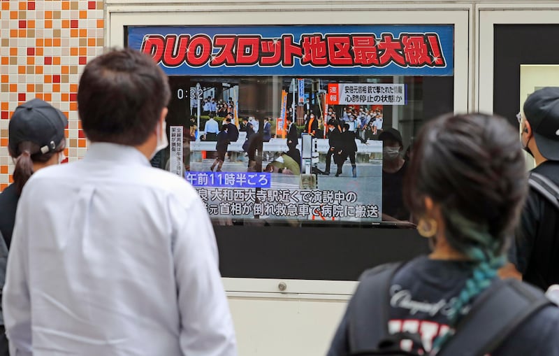 People watch TV news reports on Abe's condition after the shooting. AP