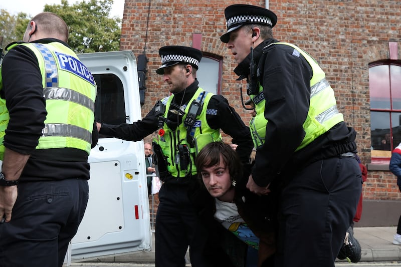 Police officers remove a man arrested for throwing an egg at King Charles III during his visit to York. Reuters