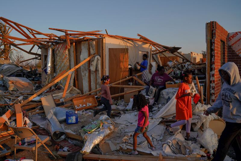 Shirley Stamps, 58, is surrounded by her grandchildren as she sits on her bed and sorts through her belongings in the wreckage of her home after thunderstorms spawning high straight-line winds and tornadoes ripped across the state in Rolling Fork, Mississippi, U. S. , March 25, 2023.  REUTERS / Cheney Orr