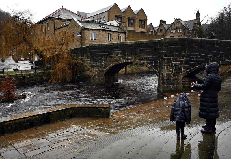 A woman and child look at the water level in Hebden Bridge. AFP
