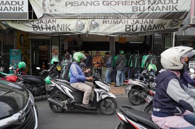 Customers and drivers for Grab Holdings Inc.'s GrabFood line up to collect orders at a Pisang Goreng Bu Nanik store in Jakarta, Indonesia, on Monday, July 15, 2019. Globally, the online food order industry has grown into a hyper-competitive field, which has led to consolidation as companies claw for a bigger slice of more than $300 billion in restaurant deliveries. Photographer: Dimas Ardian/Bloomberg
