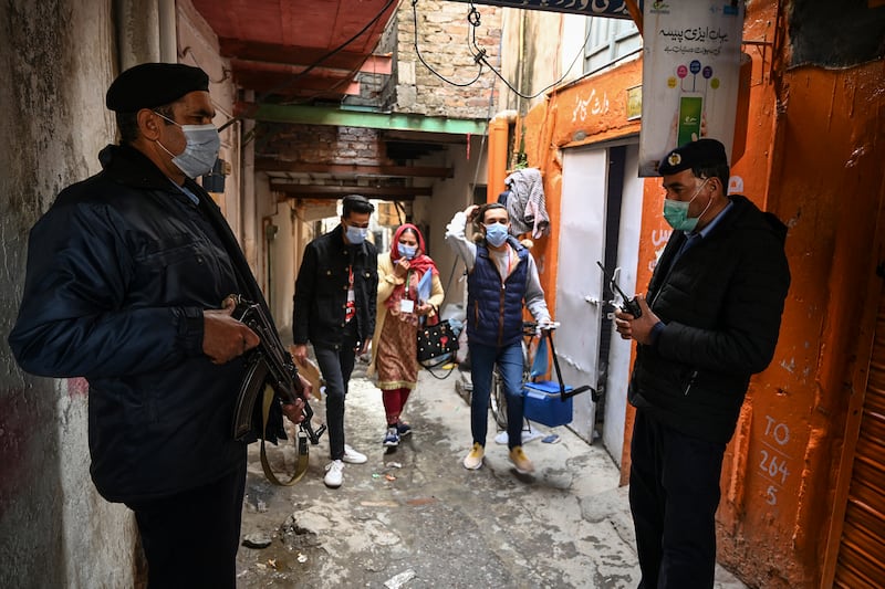 Policemen escort health workers during a polio vaccination door-to-door campaign in a slum area in Islamabad. AFP